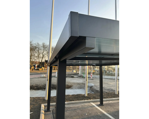 Detailní pohled na autobusovou zastávku s kovovou konstrukcí a skleněnou střechou