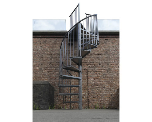 Kovové točité schodiště před cihlovou zdí