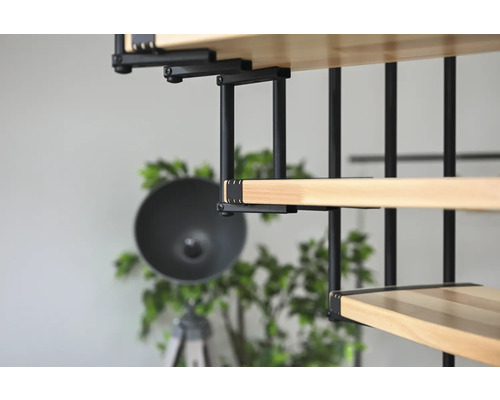 Detailní pohled na dřevěné schodiště s černým kovovým zábradlím