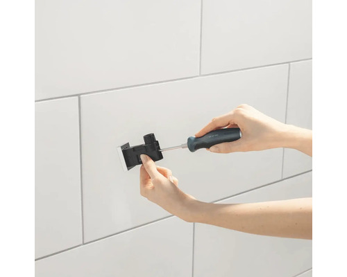 Osoba montuje upevňovací krabici na obloženou stěnu pomocí šroubováku.