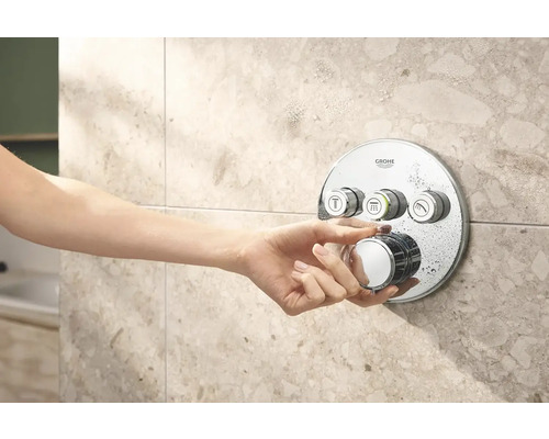 Ruka ovládá sprchovou baterii Grohe na obložené stěně