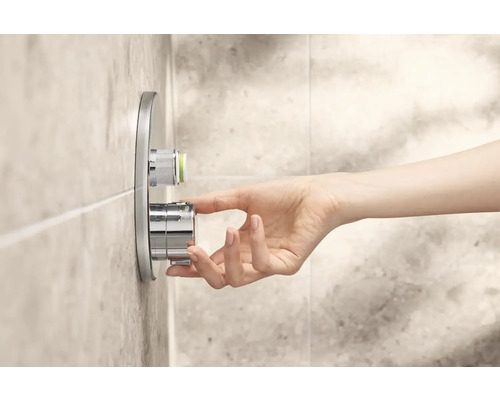 Ruka ovládá sprchovou armaturu pro regulaci teploty