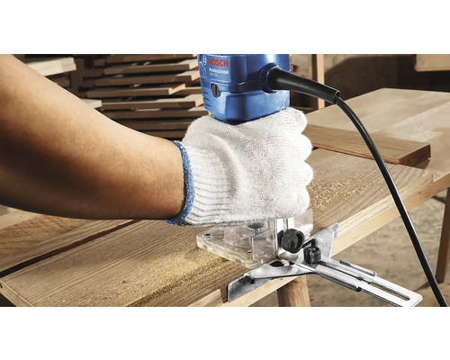 Osoba používá horní frézku na dřevěné desce. Logo Bosch.