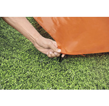 Stavění oranžového stanu s kolíkem v trávě