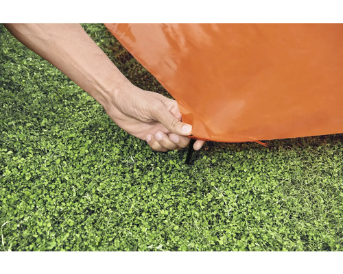 Stavění oranžového stanu s kolíkem v trávě