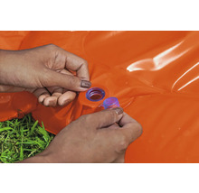 Osoba uzavírá oranžový nafukovací bazének modrou zátkou.