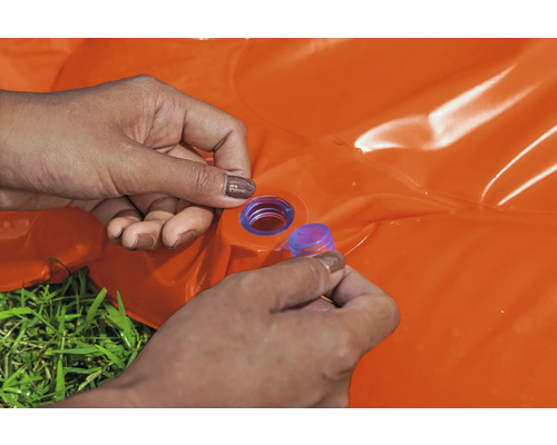 Osoba uzavírá oranžový nafukovací bazének modrou zátkou.