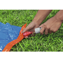 Osoba připojuje zahradní hadici k vodní skluzavce na trávníku.