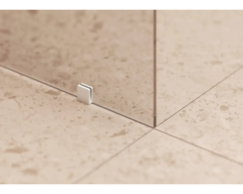 Detailní pohled na sprchový kout se skleněným prvkem a upevňovací sponou na podlaze.