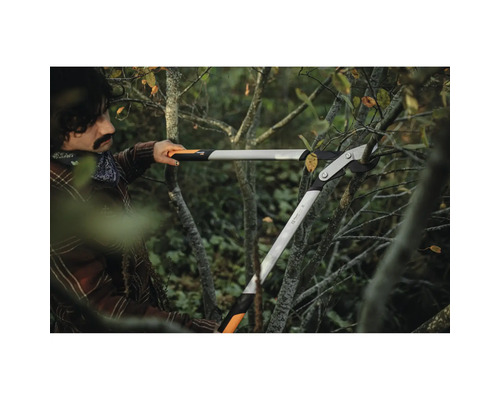 Osoba používá převodové nůžky na větve k prořezávání větví.