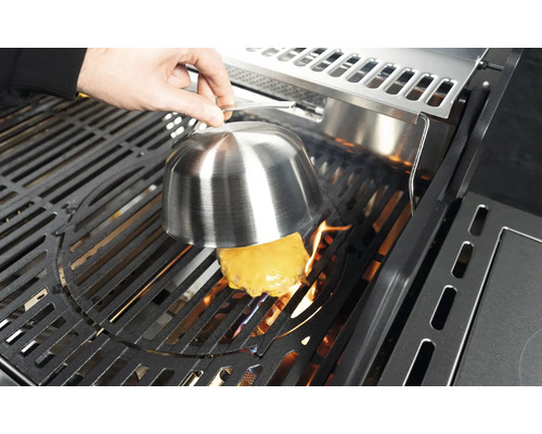 Sýrový burger se připravuje na grilu pod poklopem na tavení sýra