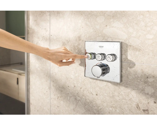 Ruka ovládá sprchovou armaturu Grohe na obkládané stěně