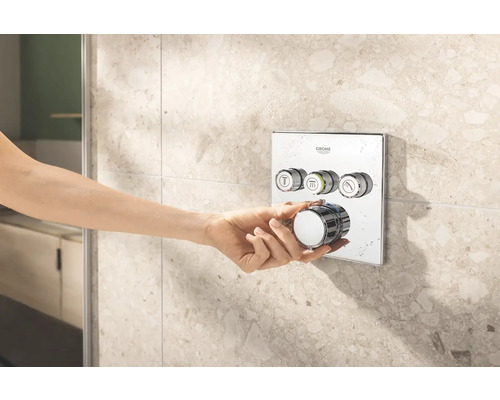 Ruka ovládá sprchovou armaturu Grohe na obložené stěně