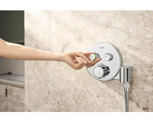 Ženská ruka ovládá sprchovou armaturu Grohe v koupelně