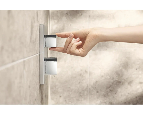 Ruka ovládá kovovou sprchovou armaturu