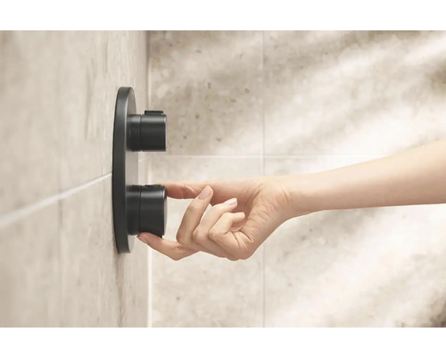 Ruka ovládá sprchovou armaturu v koupelně