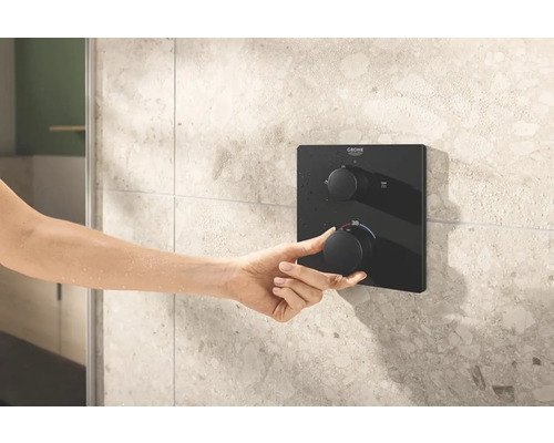 Ruka ovládá podomítkovou sprchovou baterii Grohe na obložené stěně