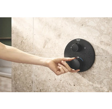 Ruka ovládá sprchový termostat Grohe na obložené stěně