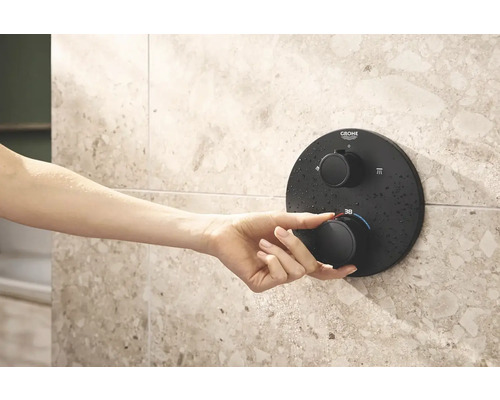 Ruka ovládá sprchový termostat Grohe na obložené stěně