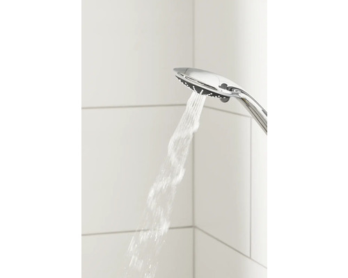 Ruční sprcha s tekoucí vodou před obkládanou stěnou