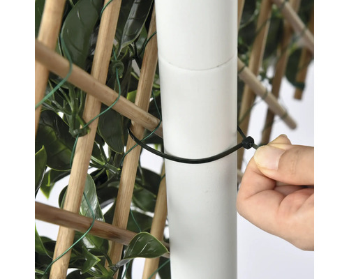 Detailní pohled na osobu připevňující zástěnu na ochranu soukromí ke sloupku pomocí stahovací pásky.