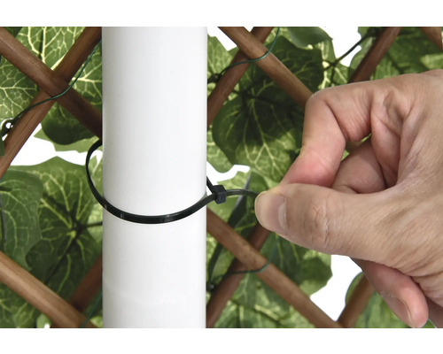 Osoba připevňuje zástěnu k sloupku pomocí stahovací pásky.