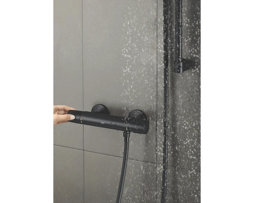 Snímek termostatické sprchové baterie s rukou nastavující regulátor teploty.