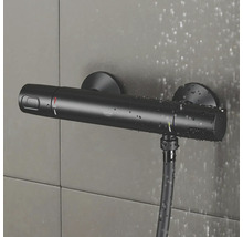 Černý sprchový termostat Grohe se sprchovou hadicí na obkládané stěně