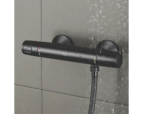 Černý sprchový termostat Grohe se sprchovou hadicí na obkládané stěně