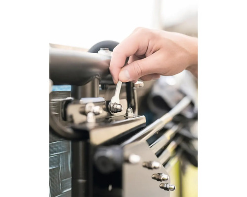 Osoba utahuje šroub klíčem.