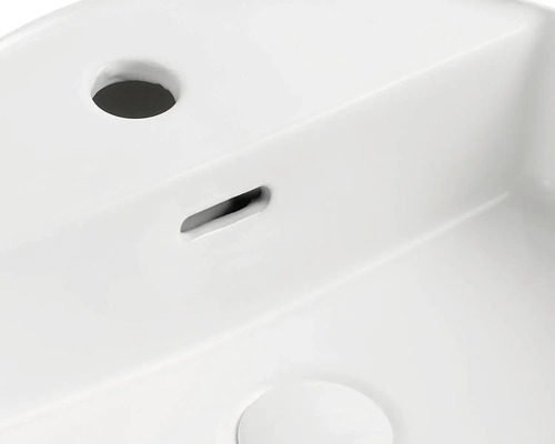 Detailní pohled na bílé umyvadlo s otvorem pro kohoutek a přepadem