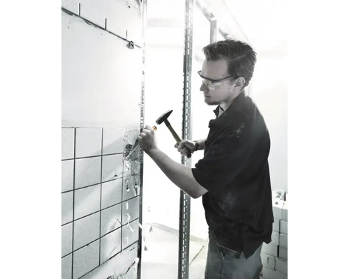 Muž odstraňuje dlaždice pomocí kladiva a dláta při rekonstrukci