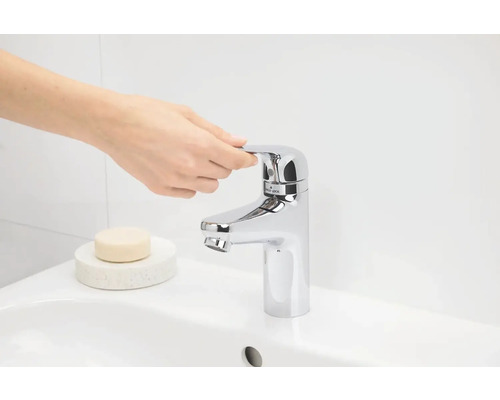 Detail umyvadla s rukou ovládající vodovodní kohoutek