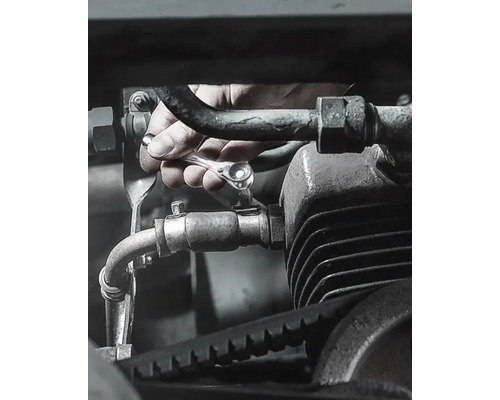 Ruka utahuje šroub na motoru ráčnovým klíčem