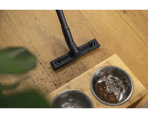 Vysavač čistí podlahu vedle misky na krmivo