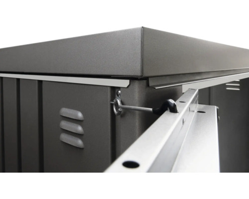 Detailní pohled na kovovou skříň na nářadí s větracími otvory a západkou dveří