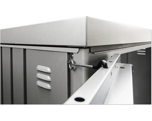 Detailní pohled na zahradní domek s kovovými prvky, větracími otvory a uzamykacím mechanismem.