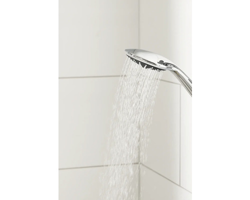 Ruční sprcha s tekoucí vodou před bíle obloženou stěnou