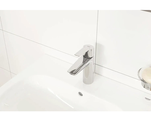 Kovová umyvadlová baterie na bílém keramickém umyvadle