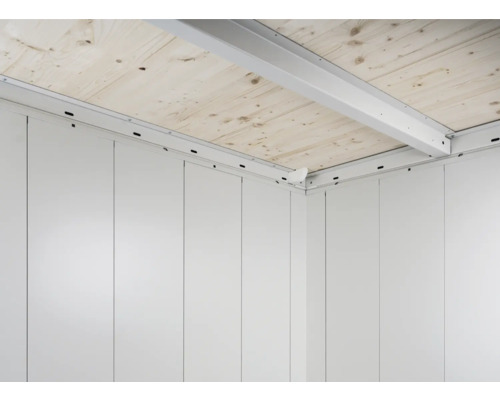 Vnitřní pohled na zahradní domek s dřevěnou podlahou a bílými stěnami.