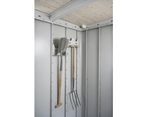 Vnitřní pohled na zahradní domek s držákem na nářadí, rýčem a vidlemi.