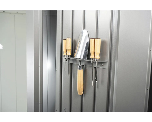 Zahradní nářadí jako lopatka a šroubováky připevněné na kovové stěně