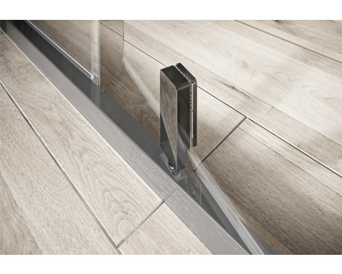 Detail sprchového koutu se stříbrným rámem a kováním na dřevěné podlaze