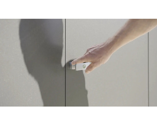 Muž ovládá zámek dveří skříně na šedé skříni.