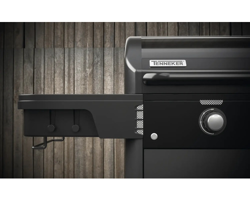 Detailní pohled na černý plynový gril s boční policí a logem Tenneker.