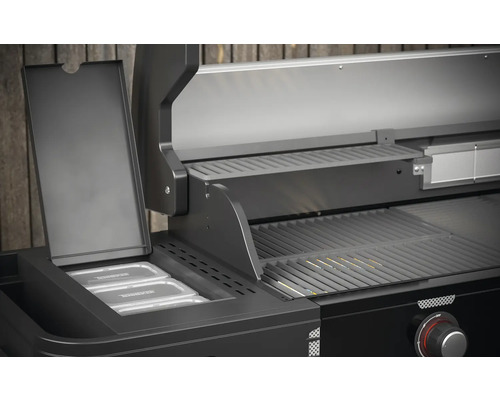 Detailní pohled na černý plynový gril s ohřívacím roštem a nádobami