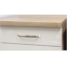 Detailní záběr zásuvkového dílu s úchytkou a deskou stolu ve vzhledu dřeva.