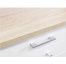 Detail komody se světle hnědou dřevěnou deskou a stříbrnými úchyty