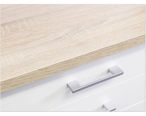 Detail komody se světle hnědou dřevěnou deskou a stříbrnými úchyty