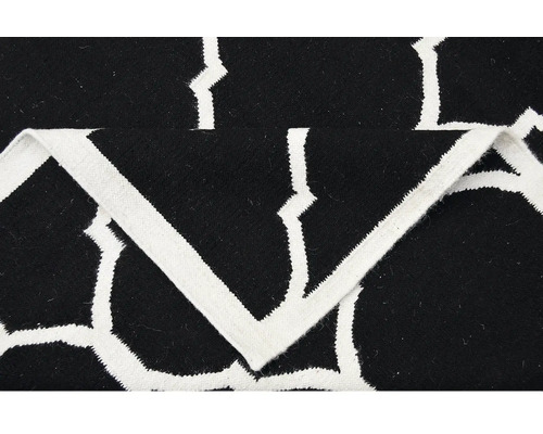 Detail černého koberce s bílým geometrickým vzorem